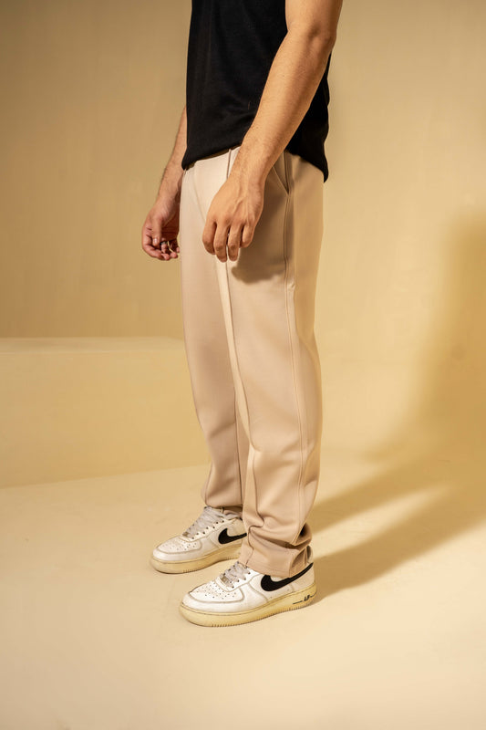 Person wearing beige pants and white sneakers on a beige background