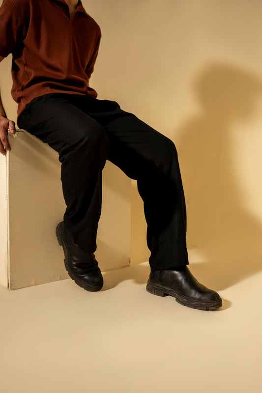 Person wearing black pants and shoes against a beige background