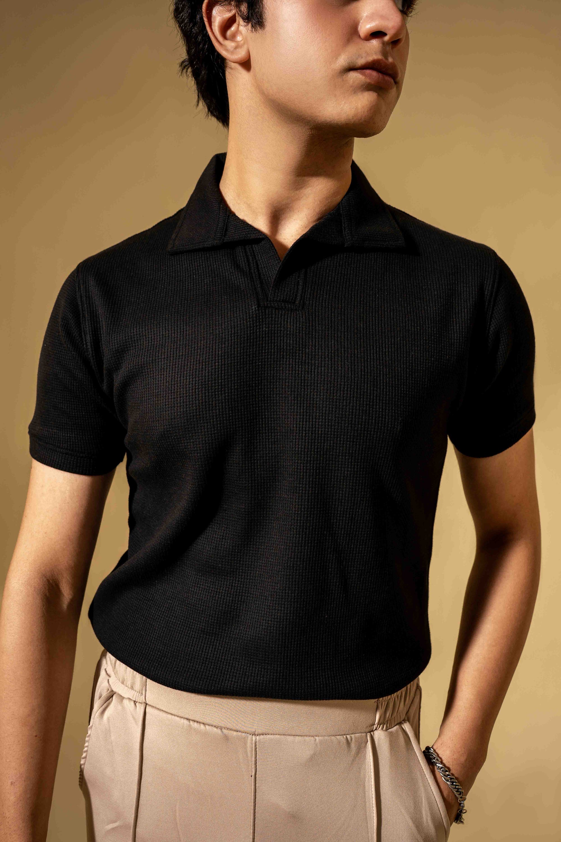 Man wearing a black polo shirt against a beige background