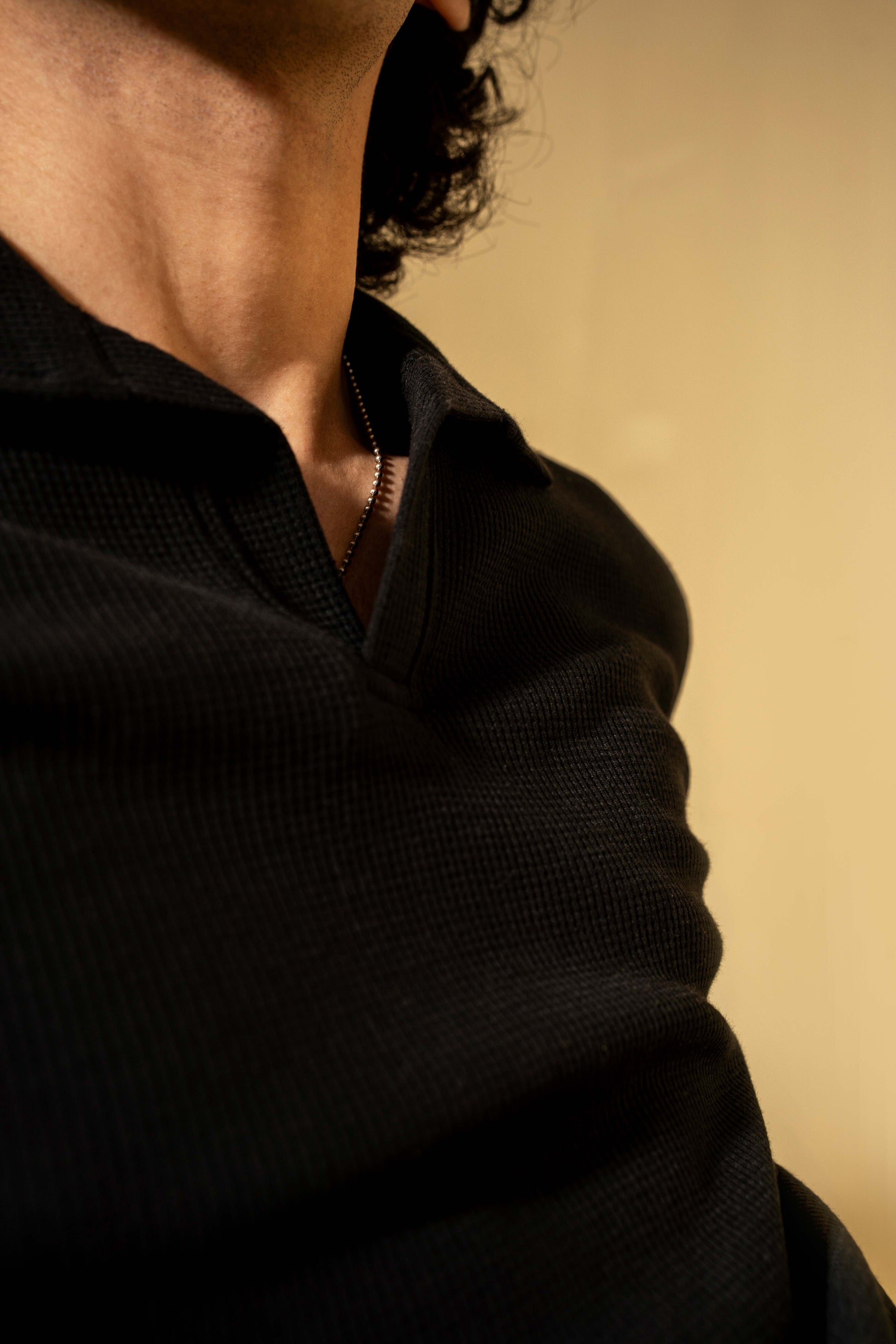 Person wearing a black shirt against a beige background