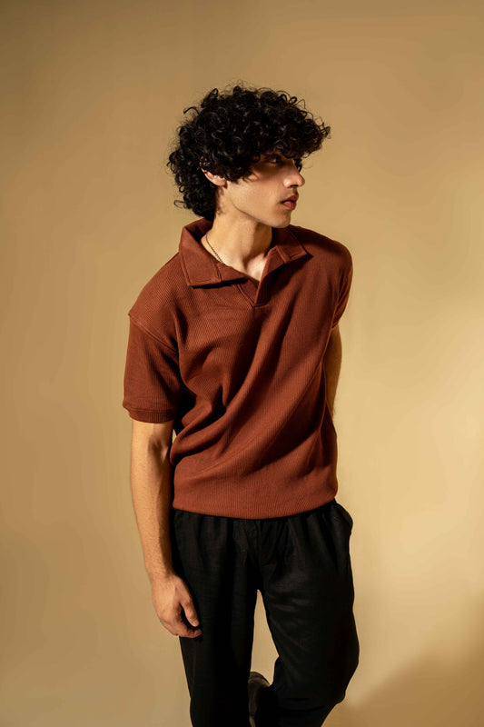 Person wearing a brown polo shirt against a beige background