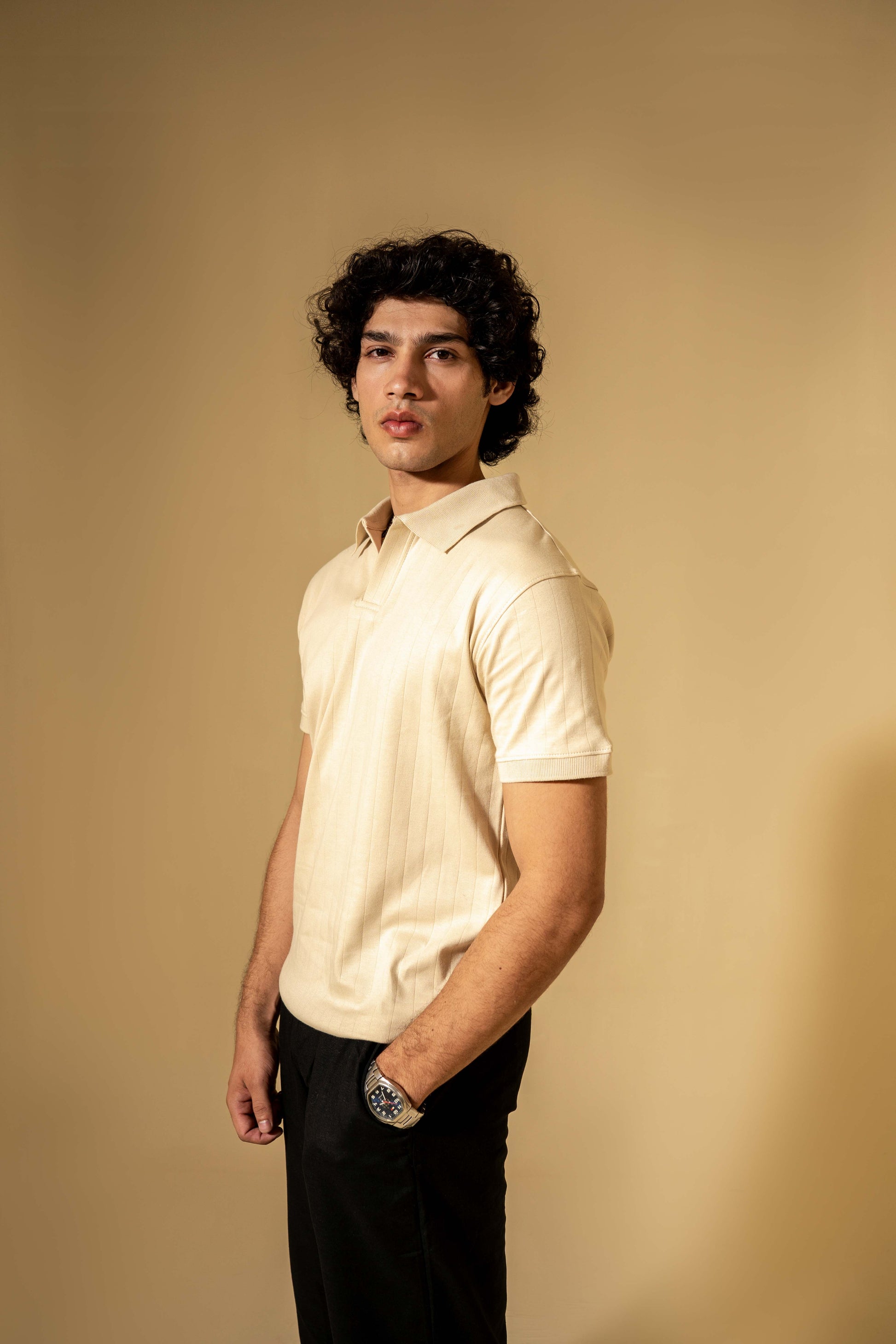 Man wearing a light-colored polo shirt against a beige background