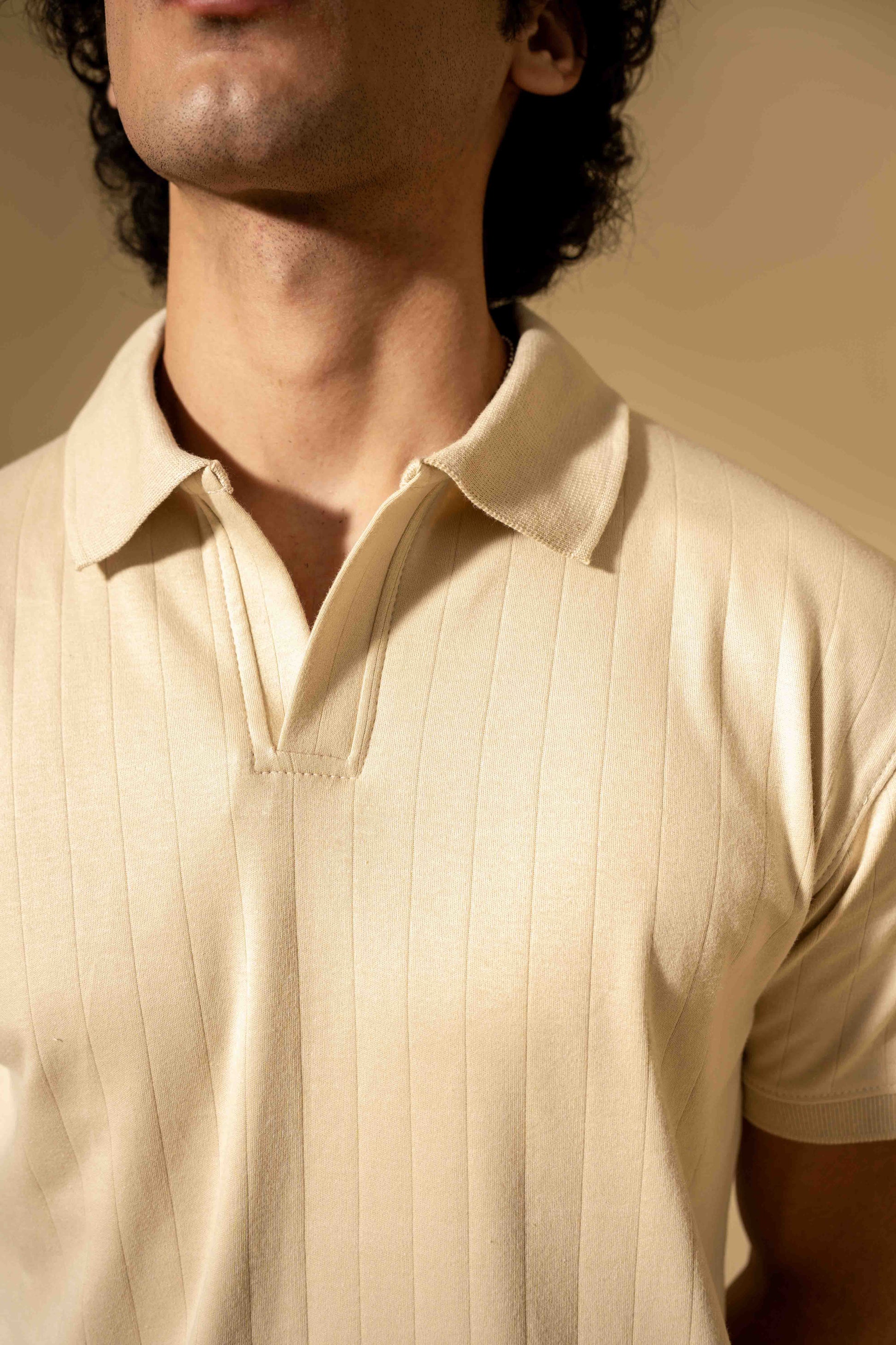 Close-up of a person wearing a beige polo shirt with a blurred background
