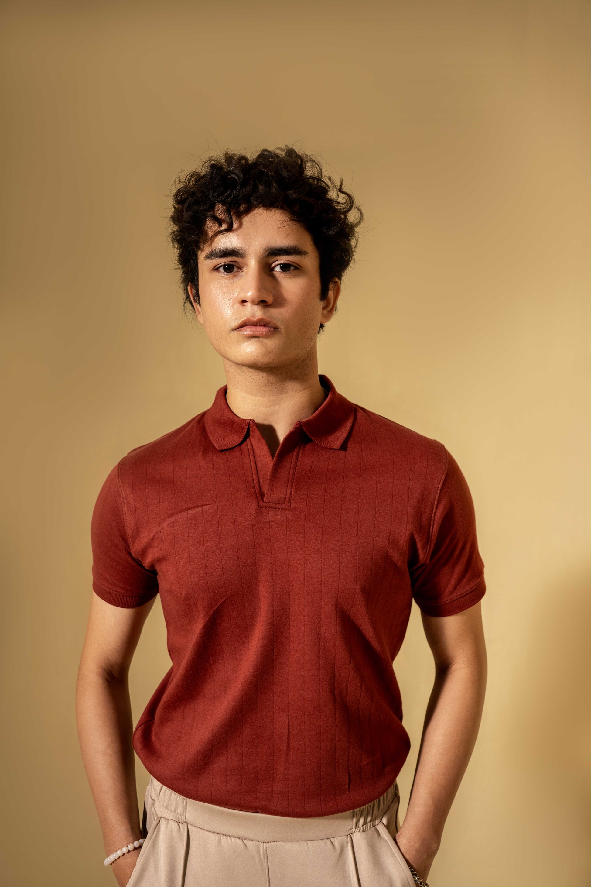 Man wearing a red polo shirt against a beige background