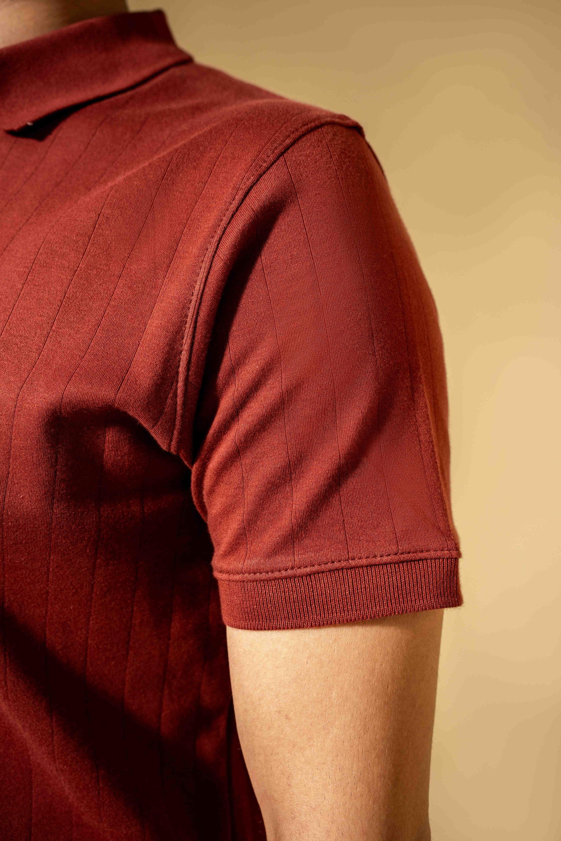 Close-up of a person wearing a red polo shirt against a beige background